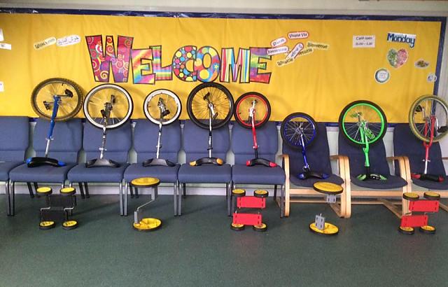 A selection of coloured unicycles, indoors.