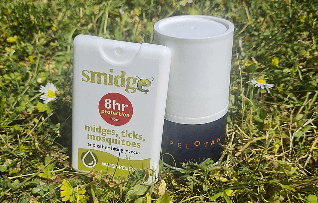 An image of a SPF Pelotan suncream and pocket Smidge insect spray bottle nestled in the grass