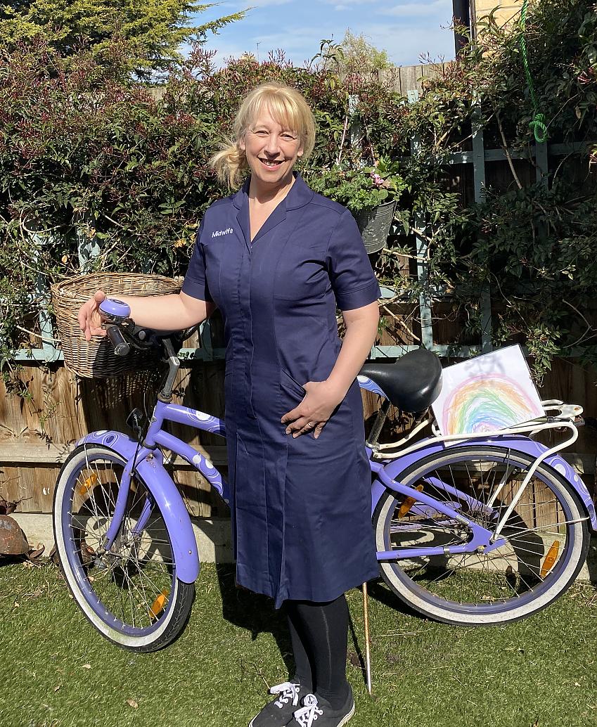 A midwife stands next to her bike