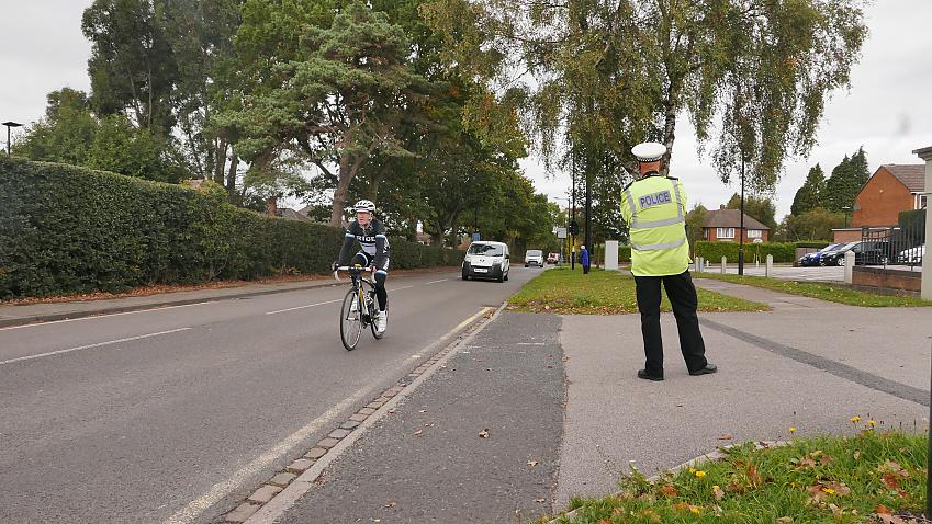 An undercover police officer dressed as a cyclist is observed by a police officer 