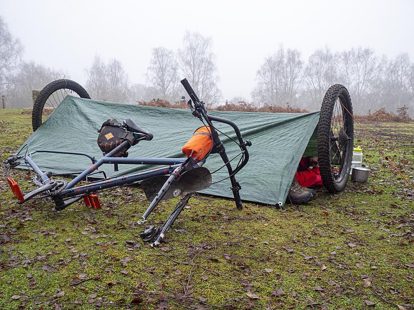 A shelter set up using a tarp and two bicycle wheels