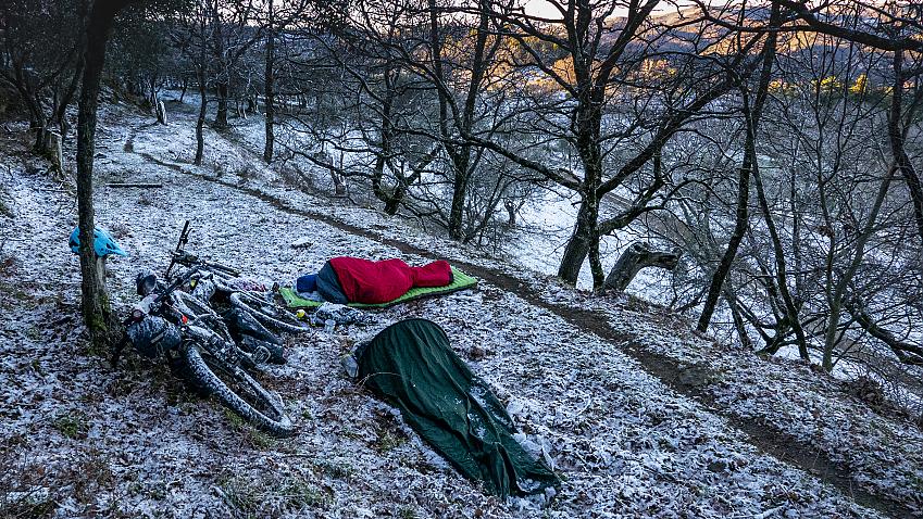A wild campsite with two bikepackers bivvying dusted in snow