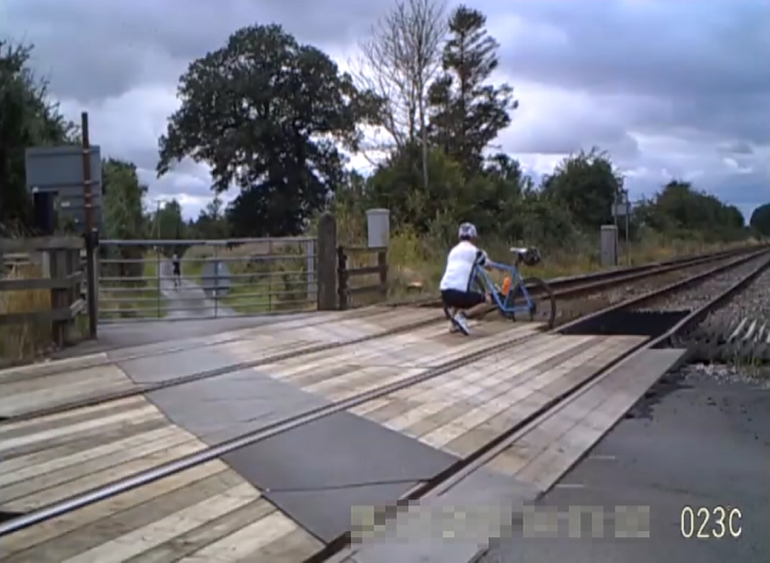 A cyclist taking a photo while on a level crossing