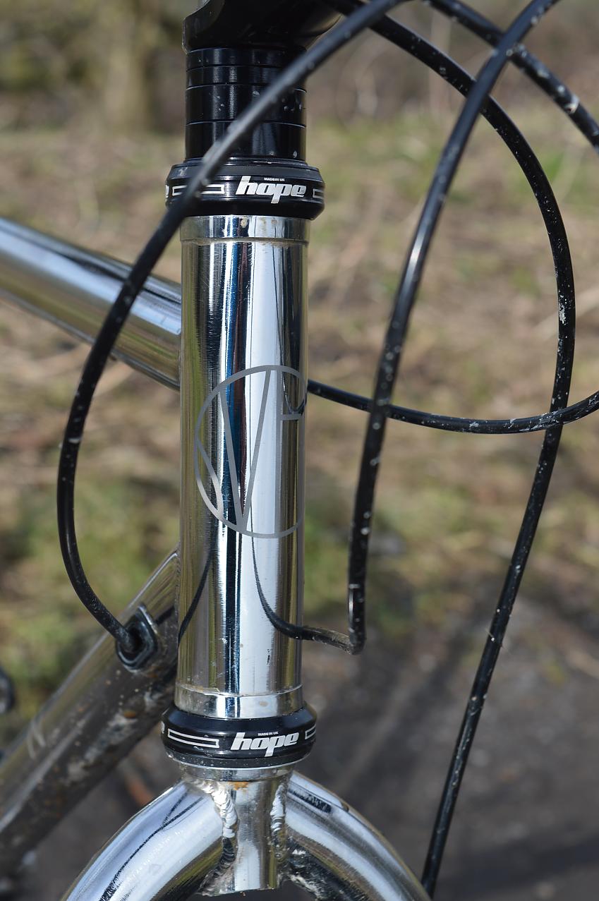 A close-up of the Pathfinder's head tube, showing the Sven Cycles logo. It's shiny untreated stainless steel