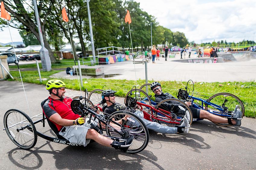 Three handcyclists sharing a joke in the park