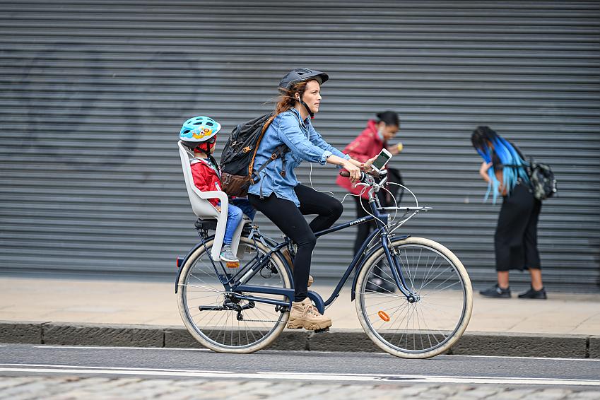 A woman rides a bicycle in Edinburgh with a child in a bike seat