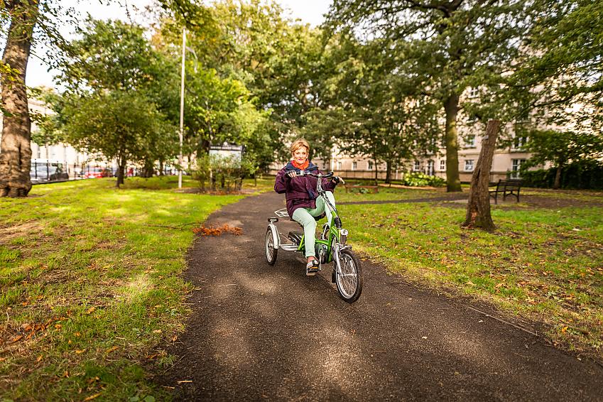 Susan Robertson riding a tricycle through a park