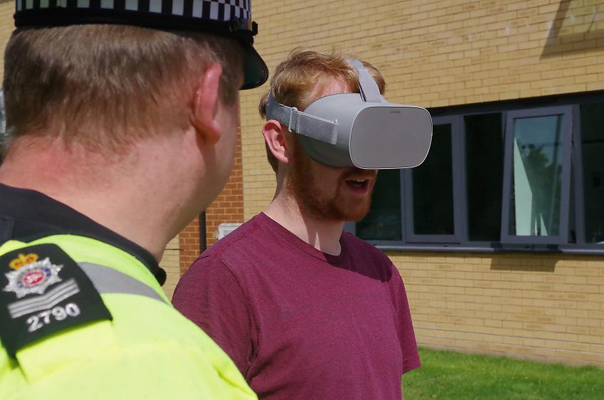 Man wearing virtual reality headset standing next to police officer