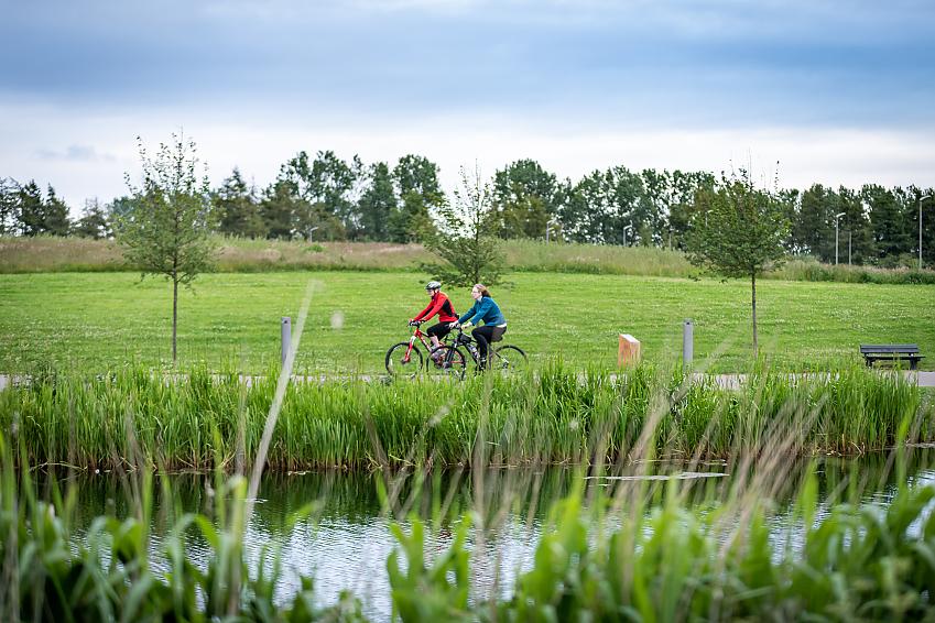 Two people riding bikes along a canal path