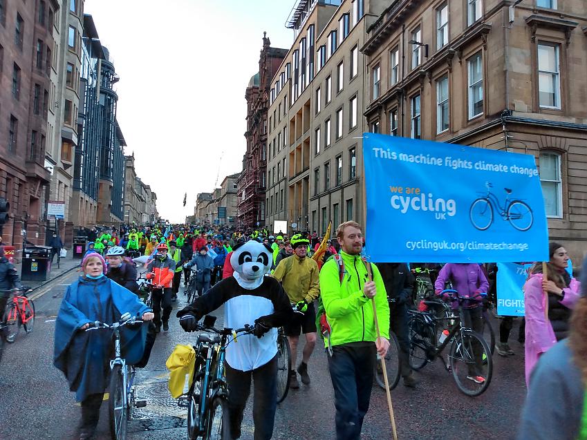 People marching pushing bikes alongside people carrying a banner saying "This machine fights climate change" in Glasgow during COP26