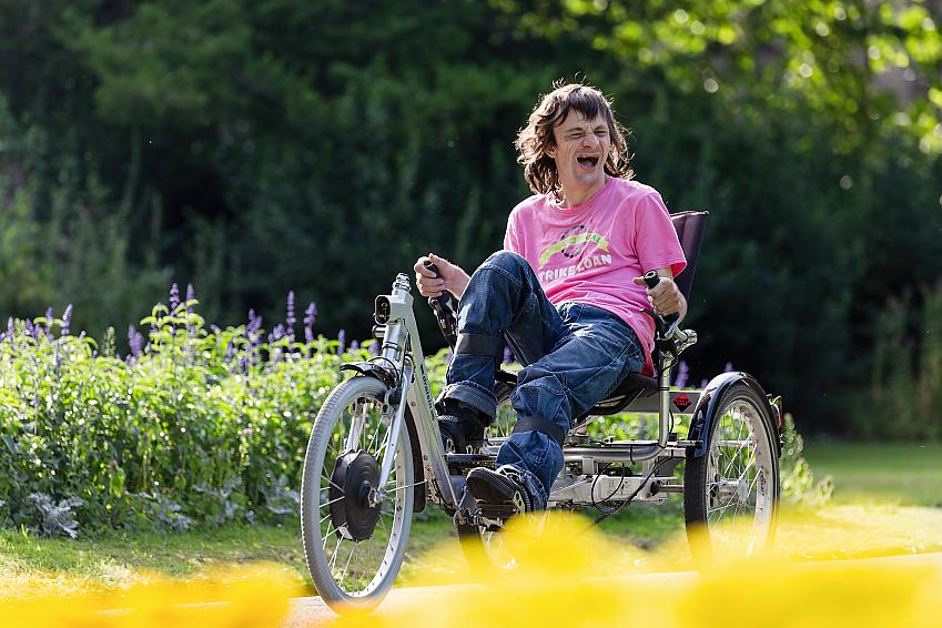 Man laughing as he rides an adapted tricycle