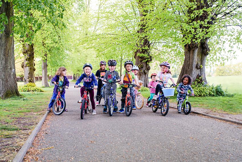 Crowd of children standing astride their bikes laughing