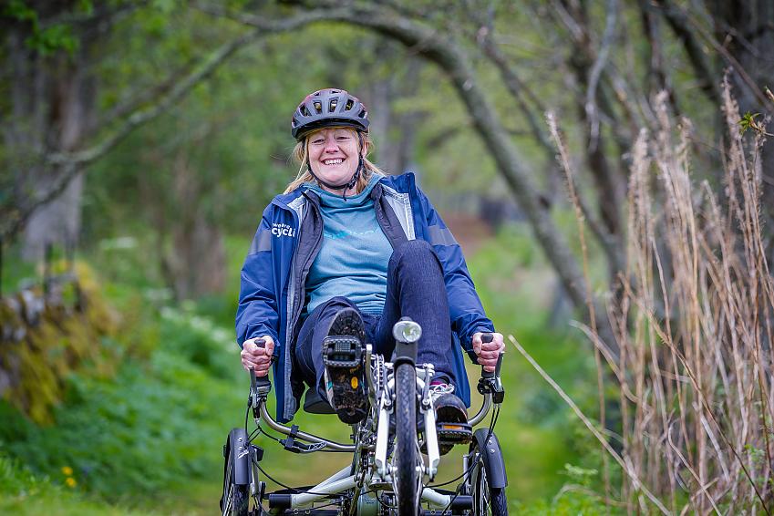 Woman smiling riding a recumbent tricycle