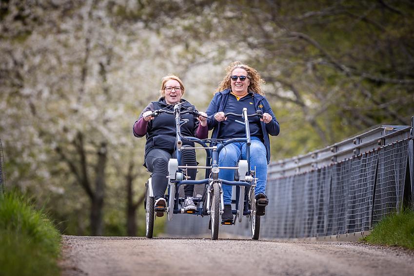 Two women riding a side-by-side tricycle