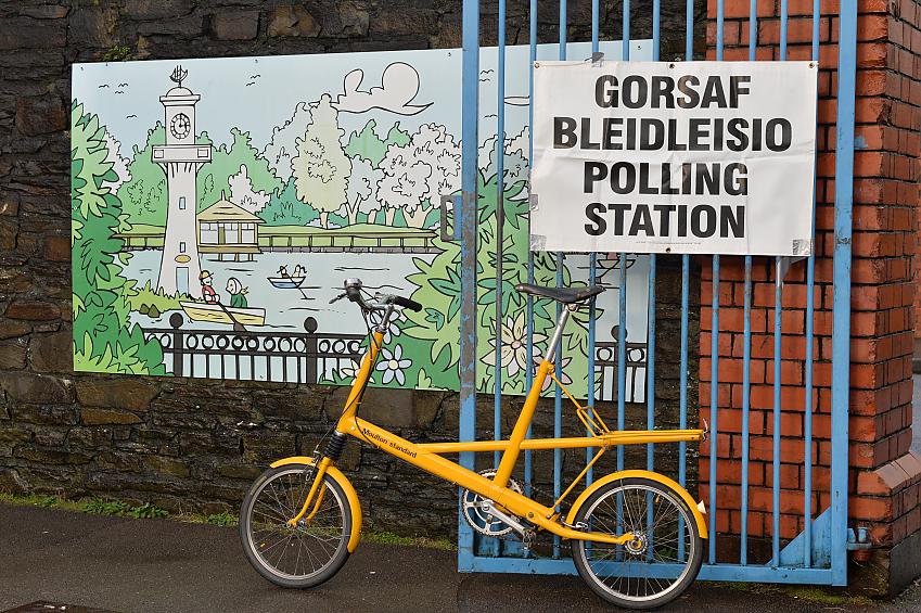 A bike in front of a mural and sign saying 'Gorsaf bleidleisio / polling station'