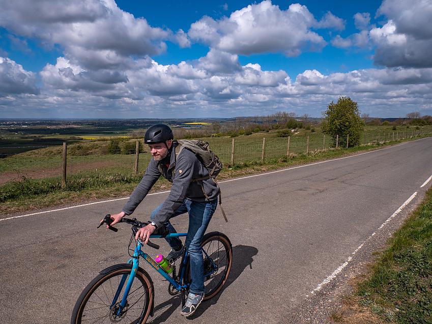 Man cycling past view of rolling hills in background