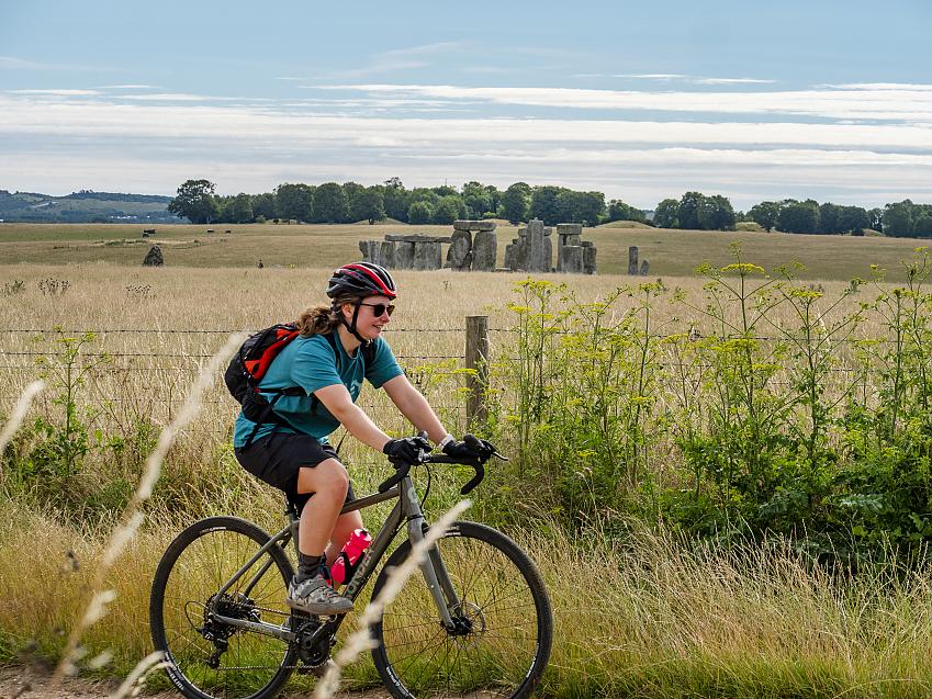 Woman cycling past Stonehenge