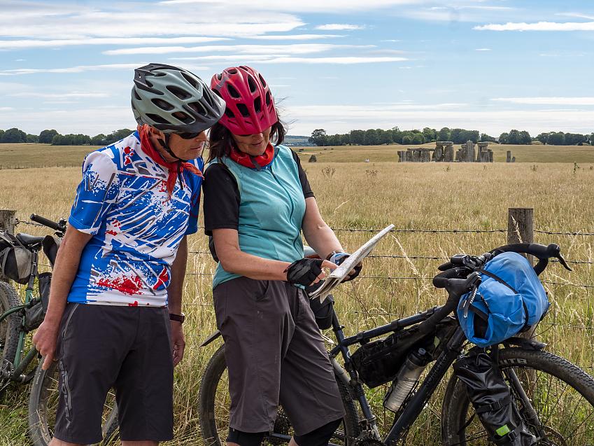 Two cyclists looking at a map with Stonehenge in the background