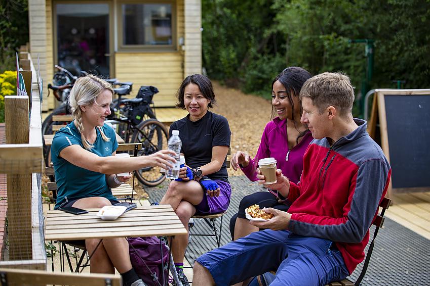 People sat at a table outside a cafe with bikes behind them