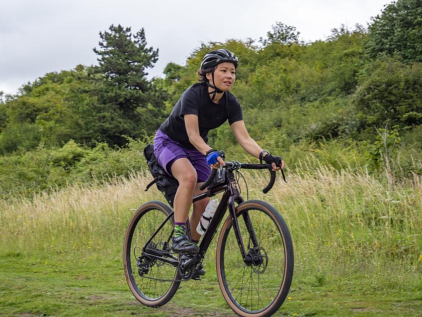 Woman riding a bike through an area of grassland and trees