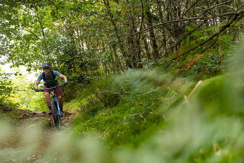 Woman riding down a mountain bike trail in a forest