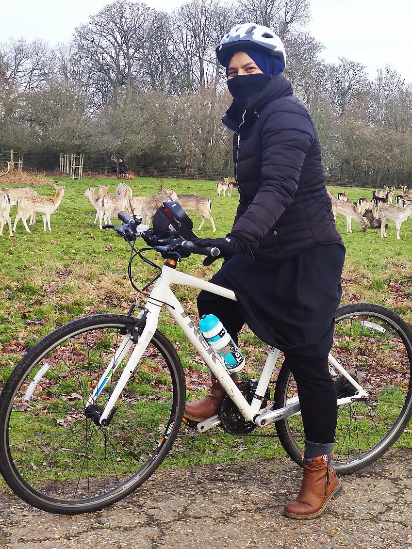 Syeda on her bike in front of a field of deer
