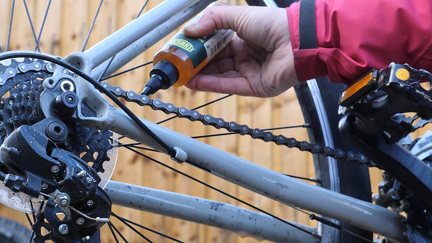 A close-up of someone applying grease to a bicycle chain