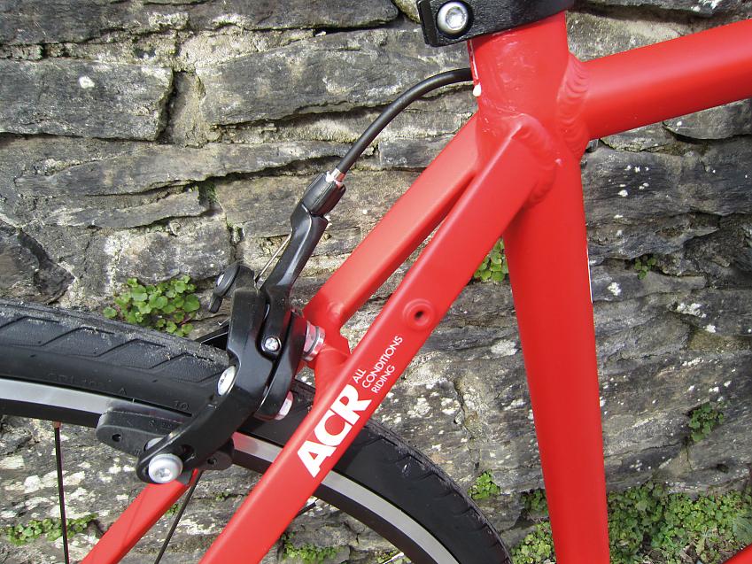 A close-up showing the B’Twin Triban 500's eyelets for mounting a rear rack; they're in the seat stays, near the top close to where the stays meet the seatpost and seat tube. The bike is red