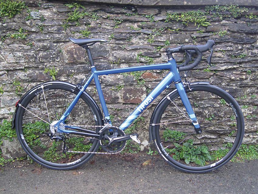 A blue road bike leaning against a stone wall