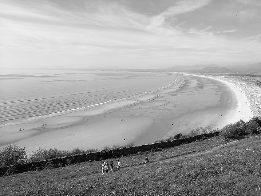 A black and white shot of Harlech beach, with the village of Cricceith in the distance