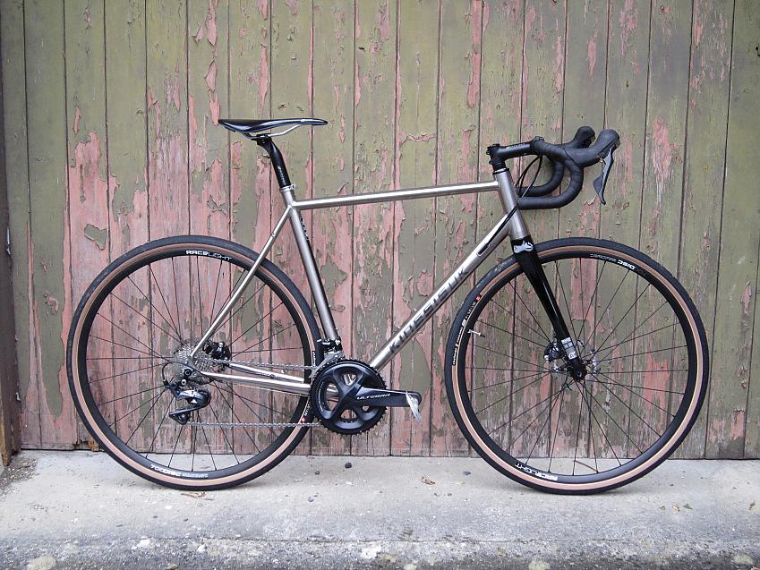 The Kinesis GTD, a pale gold touring bike leaning against a fence