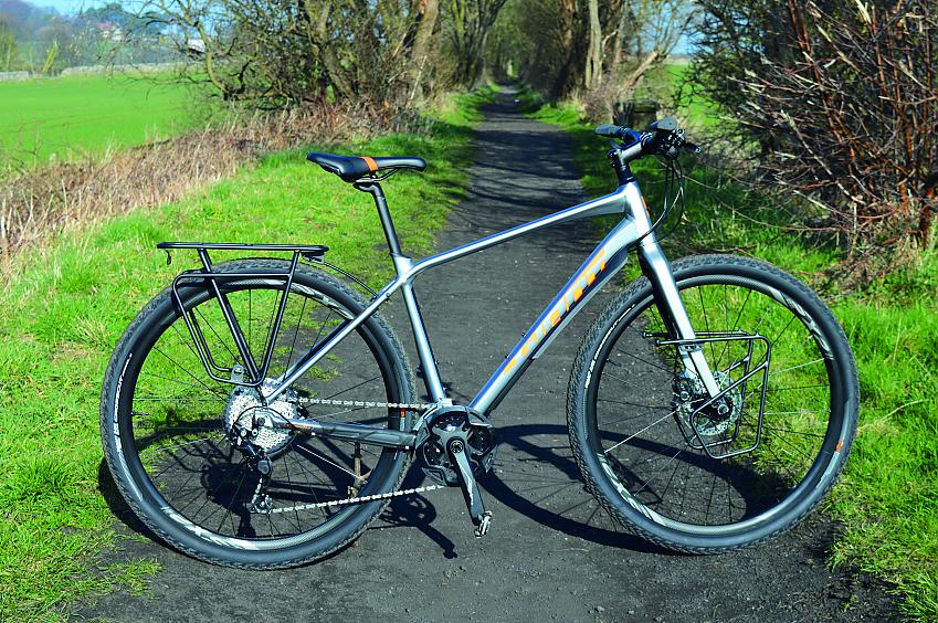 Giant Toughroad SLR1, a grey and purple gravel bike, propped up on a gravel path