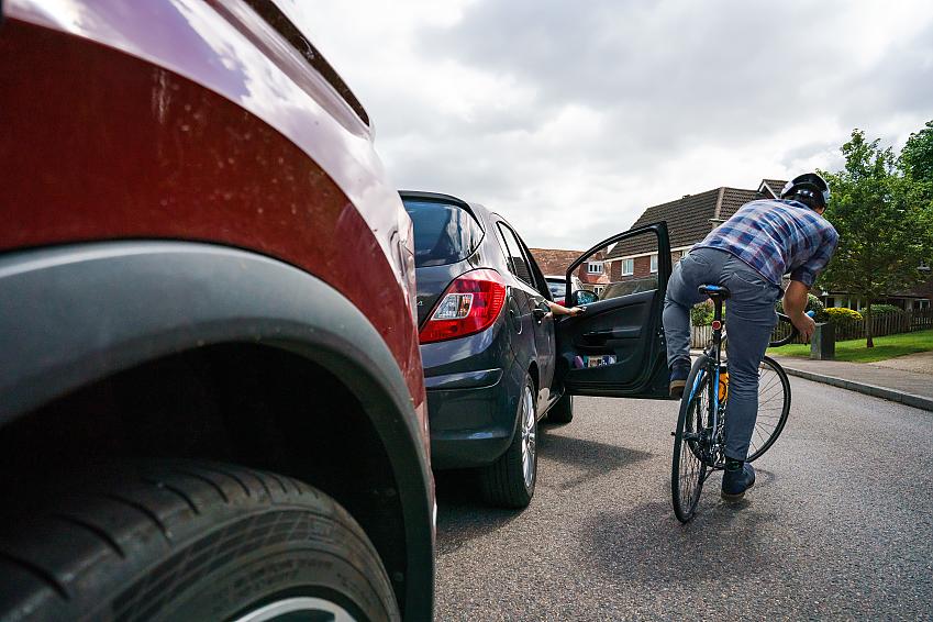 A motorist opening a car door into a cyclist