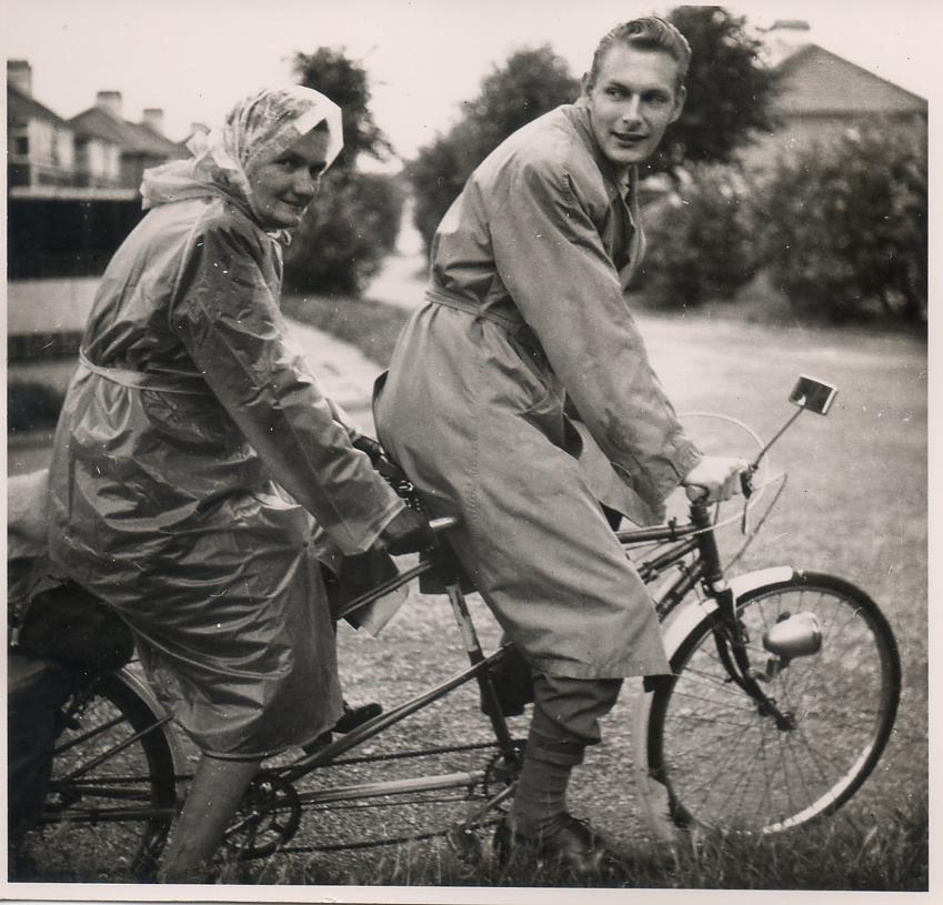 A scan of an old black and white photo showing a man and a woman on a tandem, with the woman at the back