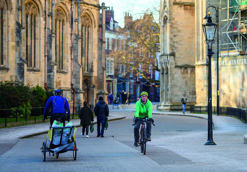 People are cycling and walking along a traffic-free street in York