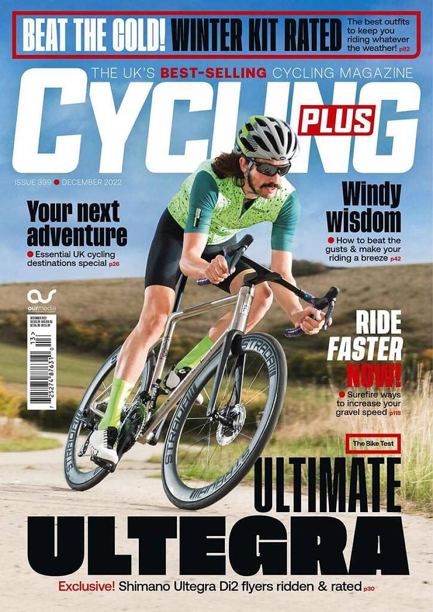 Cycling Plus cover, December 22 issue, showing a man with long hair and a moustache riding fast down a hill. He's wearing black cycling shorts and a green cycling jersey; he's riding a racing bike