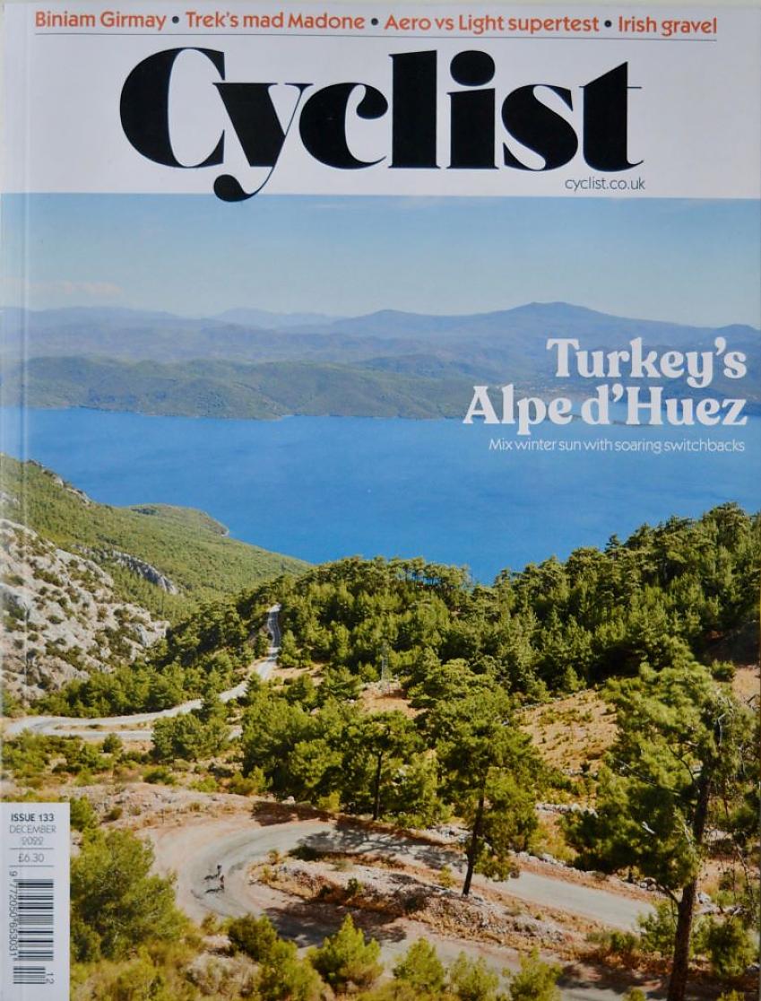 Cyclist magazine cover, December 22 issue, showing the Alpe d'Huez in Turkey, a long winding downhill road with lots of trees, heading down towards a bay