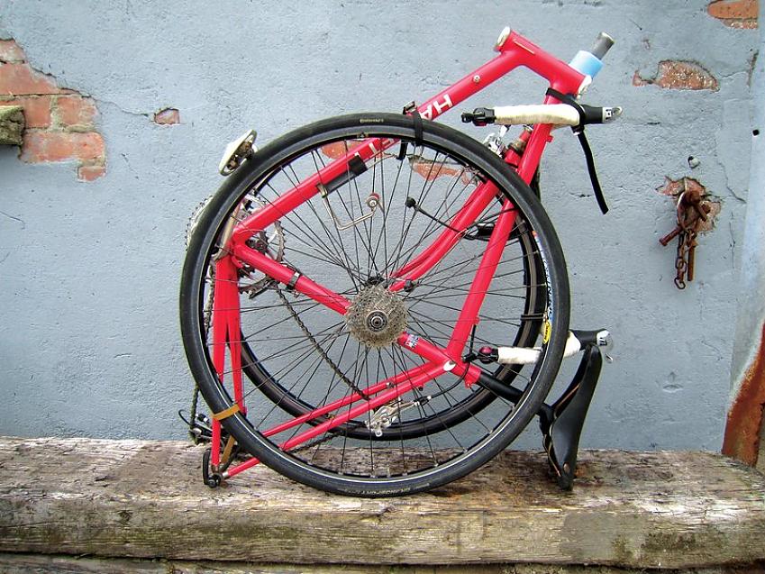 A full-size red road bike disassembled and strapped together