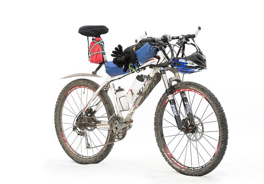 A muddy bike with water bottles and packed frame bags