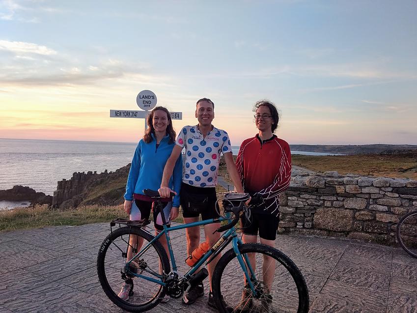A man posing with his son and daughter and bicycle at Land's End