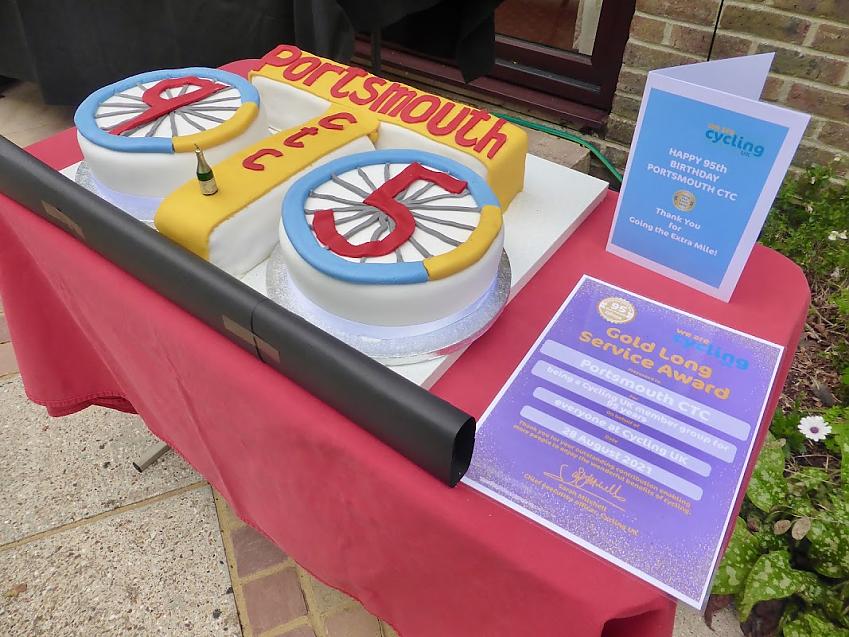 A close-up of a very large cake for Portsmouth CTC's 95th birthday. It's made up of two round parts to represent wheels and a T shape decorated with the words Portsmouth CTC