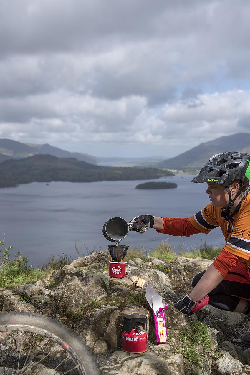 A bikepacking cyclist pouring water onto a camping coffee maker
