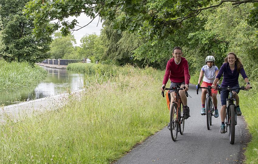 Three people cycling along a canal path
