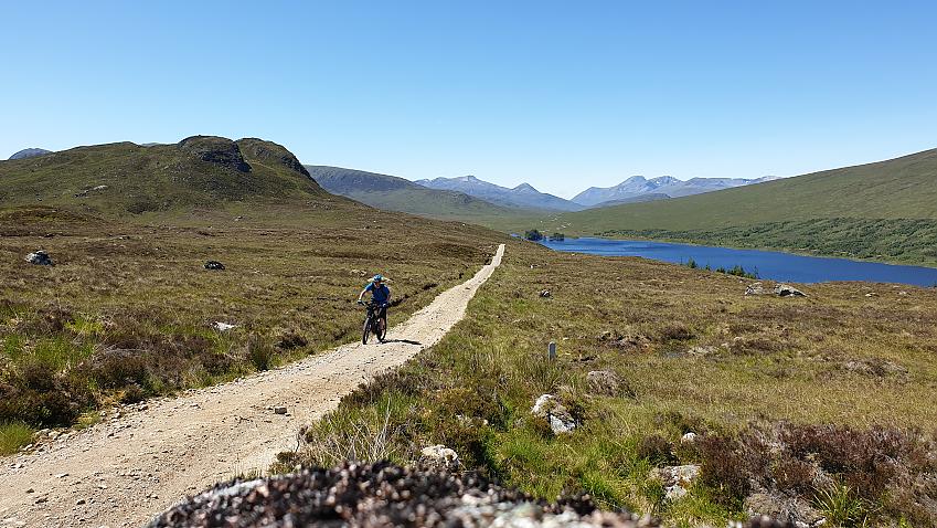 A lone figure riding amongst mountains and lochs