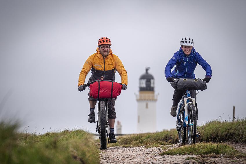 A man and woman ride away from Cape Wrath lighthouse