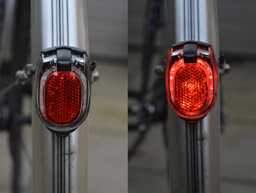 An amalgamated shot of a red rear bike light mounted on a mudguard, the left isn't lit up, the right is