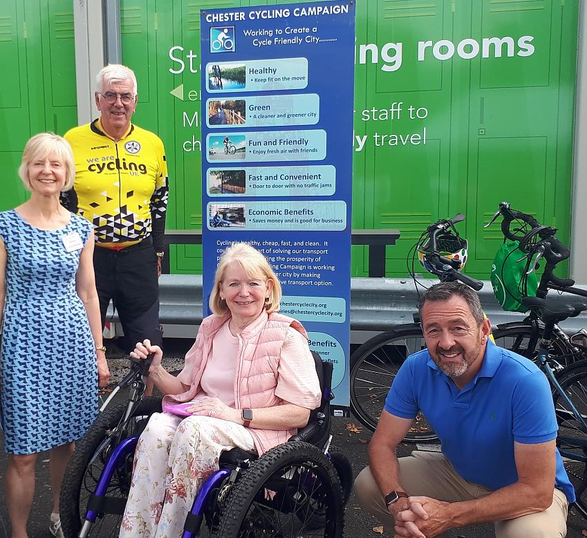 Two men and two women pose by a banner for the Chester Cycling Campaign. One of the ladies is in a wheelchair. They are all smiling at the camera