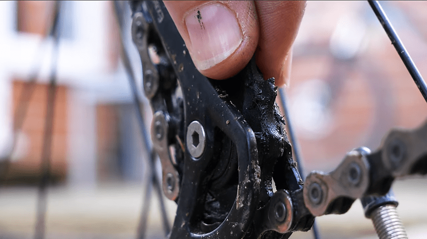 A close-up of a bicycle chain showing a lot of dirt on the chain