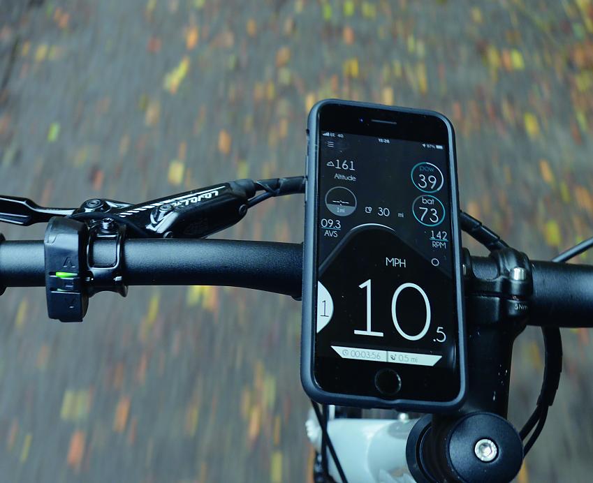 A close-up showing a smartphone attached to the handlebar of the eJimi, with the ebikemotion app displayed on the screen