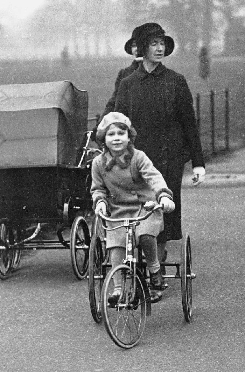 A young Queen Elizabeth II rides her tricycle in Windsor Park